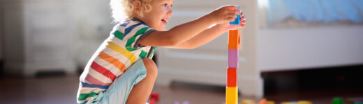 Child playing with colorful toy blocks. Kids play.
