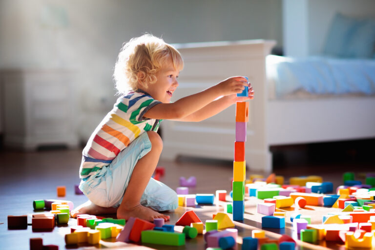 Child playing with colorful toy blocks. Kids play.